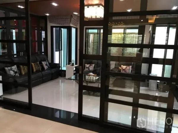 独立式住宅 出租在Khlong Toei, Bangkok - 玻璃隔断的会客区，黑色皮沙发与亮面地砖。