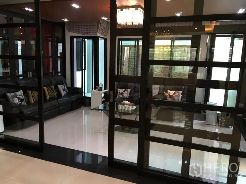 独立式住宅 出租在Khlong Toei, Bangkok - 玻璃隔断的会客区，黑色皮沙发与亮面地砖。