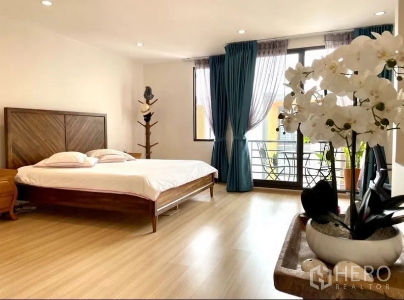 Townhouse for rent in Suan Luang, Bangkok - Spacious primary bedroom with balcony access and floor-to-ceiling windows.
