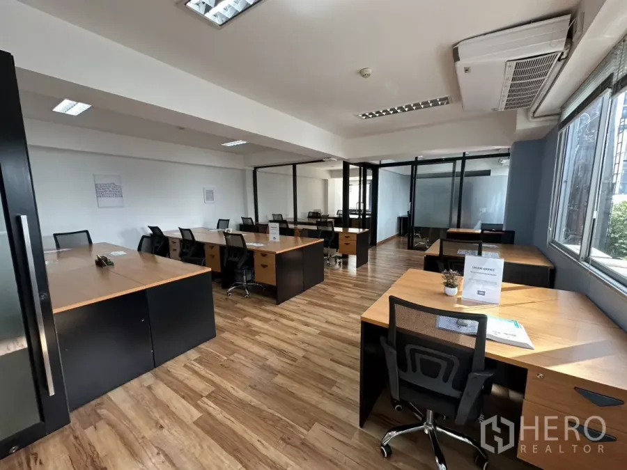 Office Space for rent in Watthana, Bangkok - Bright open-plan office with wood flooring, rows of desks, large windows and glass-partitioned rooms.
