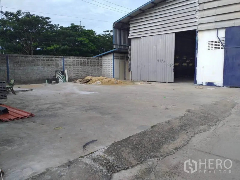 货栈 出租在Pak Kret, Nonthaburi - 仓库侧面带大型卷门与硬化场地，适合卡车进出。