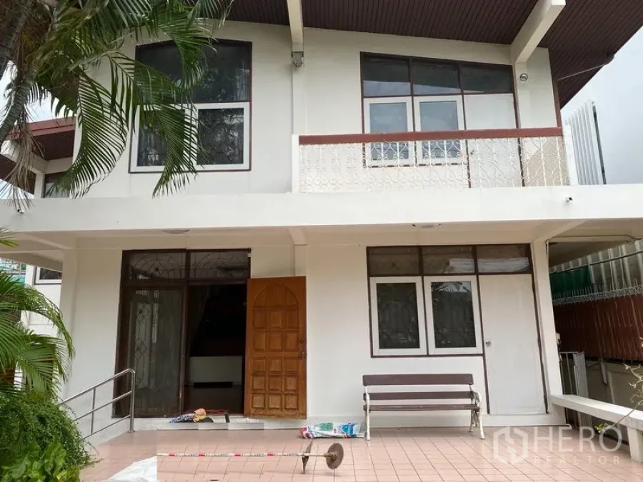Detached House for rent in Khlong Toei, Bangkok - Front facade of a two-storey detached house with balcony and a tiled patio.