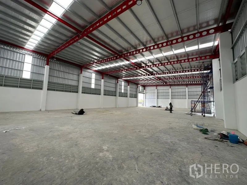 Warehouse for rent or sale in Lam Luk Ka, Pathum Thani - Bright wide‑span warehouse hall with open loading door at the far end.