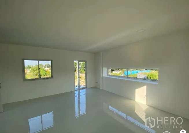 Warehouse for sale in Sai Noi, Nonthaburi - Bright upstairs office with glossy tile flooring, large windows, and a glass door opening to a small balcony.