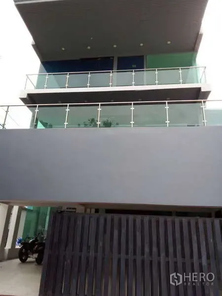 Detached House for sale in Lat Phrao, Bangkok - Modern three-storey detached house with glass balconies and gated carport in Lat Phrao, Bangkok.