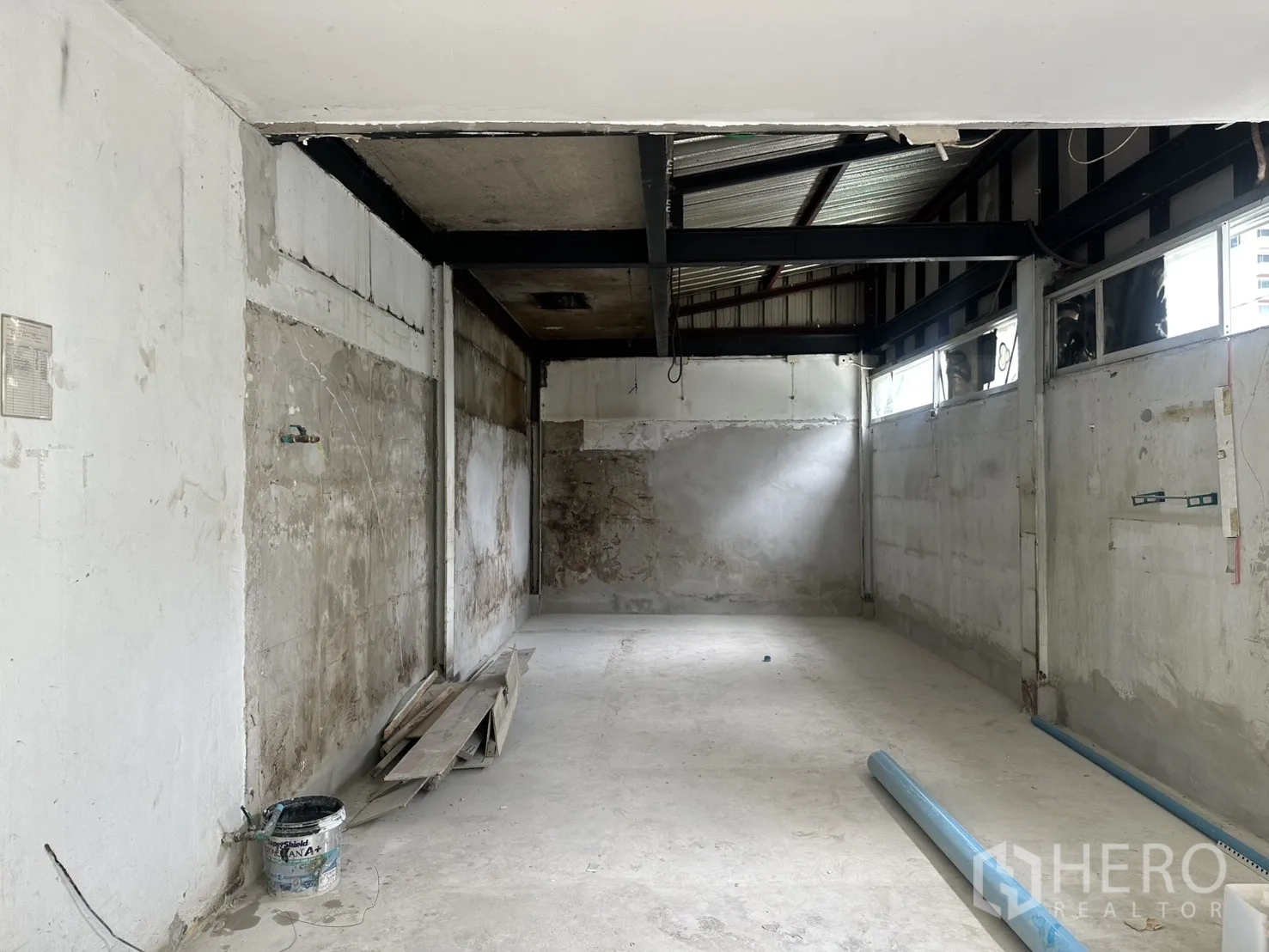 Retail Space for rent in Sathon, Bangkok - Unfinished retail interior with concrete floor, exposed steel beams, high side windows, and construction materials on the floor.