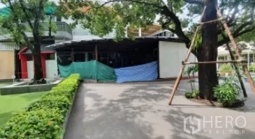 Retail Space for rent in Khlong Toei, Bangkok - Walkway lined with hedges leading to a covered retail unit beneath mature trees.