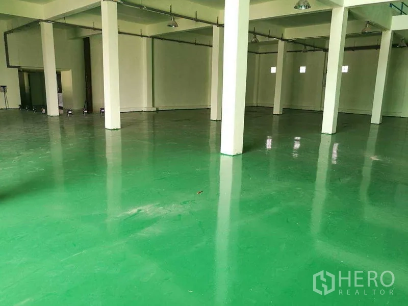 工厂 出租在Mueang Samut Sakhon, Samut Sakhon - 宽敞生产车间，绿色环氧地坪、白色立柱与高吊顶照明。