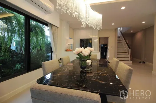 Detached House for rent in Prawet, Bangkok - Dining area featuring a black marble table beneath a crystal chandelier.
