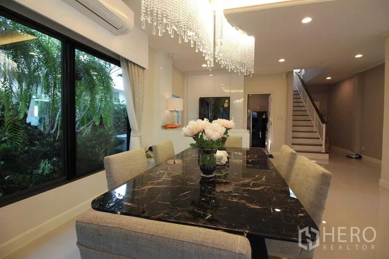 Detached House for rent in Prawet, Bangkok - Dining area featuring a black marble table beneath a crystal chandelier.