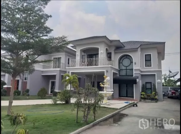 Detached House for sale in Lam Luk Ka, Pathum Thani - Second two-storey house with balcony, round feature window and a courtyard fountain.