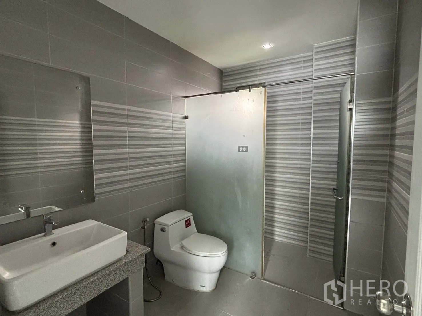 Warehouse for rent or sale in Wang Thonglang, Bangkok - Modern bathroom with glass shower screen and striped tiles.