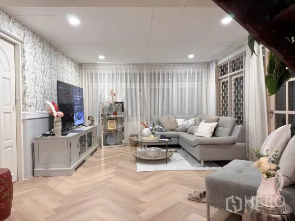 Detached House for rent in Huai Khwang, Bangkok - Bright living room with L-shaped sofa, TV console and herringbone wood floor.