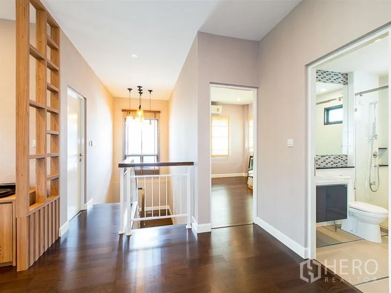 Detached House for rent or sale in Prawet, Bangkok - Upper hallway with staircase, pendant lights and an adjacent bathroom.