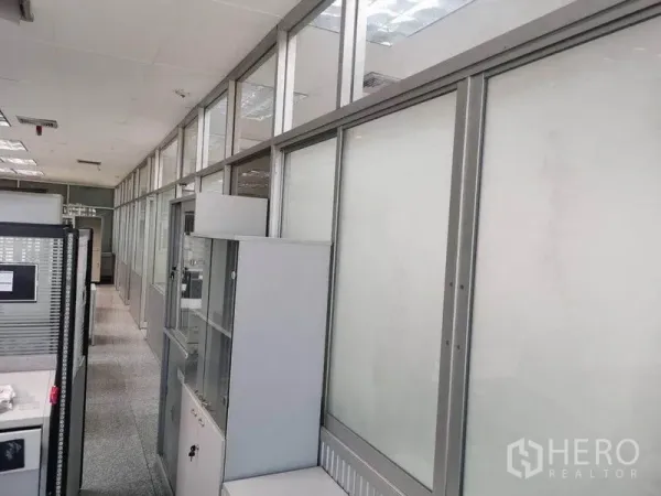 Office Space for rent in Bang Na, Bangkok - Hallway lined with frosted glass partitions and storage cabinets inside the office space.