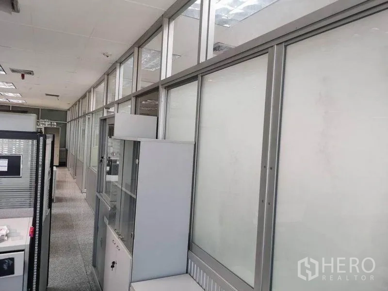 Office Space for rent in Bang Na, Bangkok - Hallway lined with frosted glass partitions and storage cabinets inside the office space.