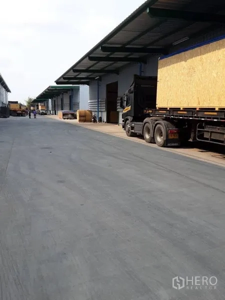 Warehouse for rent in Bang Phli, Samut Prakan - Wide concrete loading road with covered bays and a long-haul truck beside modern warehouses in Bang Phli.