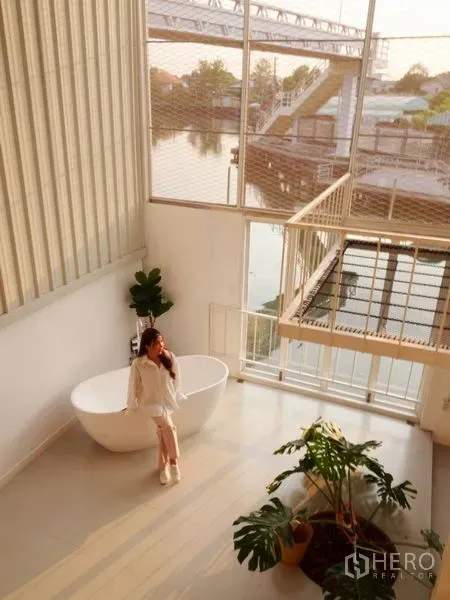 Townhouse for rent in Khlong Toei, Bangkok - Double-height atrium with freestanding bathtub, floor-to-ceiling windows and canal view in a Bangkok townhouse near BTS On Nut.