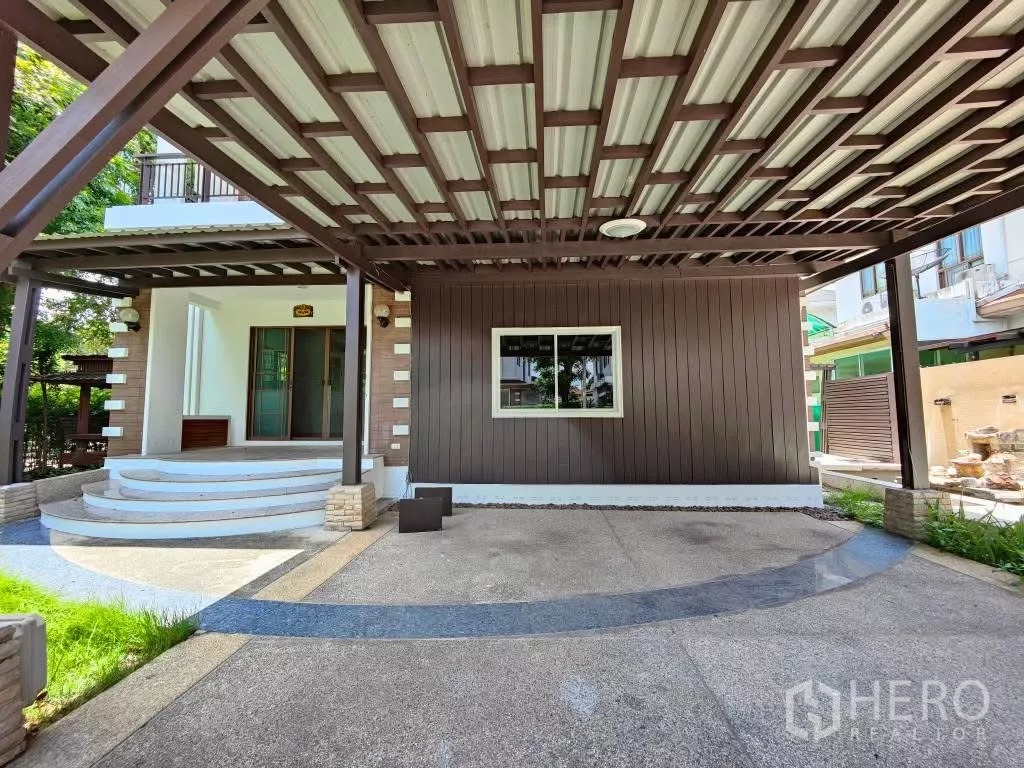 Detached House for rent or sale in Mueang Nonthaburi, Nonthaburi - Covered parking and front porch with wood beams, textured concrete and a side entrance.
