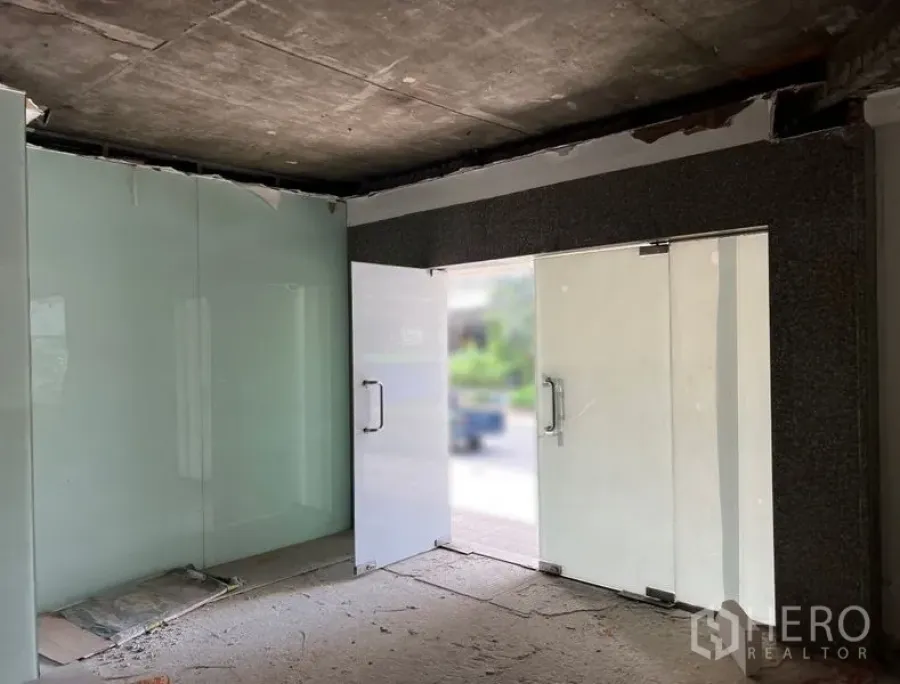 零售空间 出租在Watthana, Bangkok - 金属框玻璃双开门的店铺入口，面向街景。