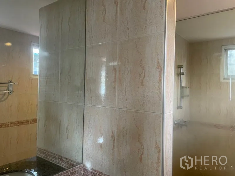 独立式住宅 出租在Huai Khwang, Bangkok - 浴室铺米色墙砖，玻璃隔断与台面洗手盆，设通风小窗。