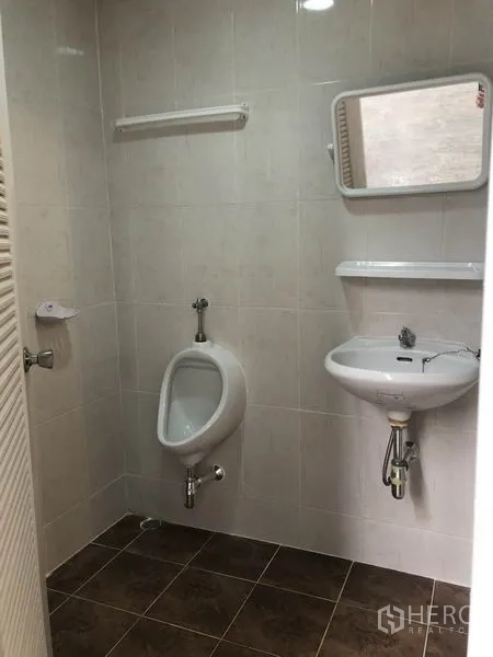 Factory for rent in Pak Kret, Nonthaburi - Tiled restroom with wall-mounted sink and urinal in the factory.