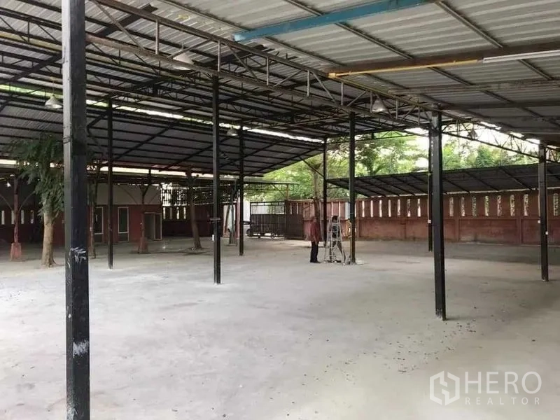 Warehouse for rent or sale in Khlong Sam Wa, Bangkok - Spacious covered storage area with steel columns and wide concrete loading space.