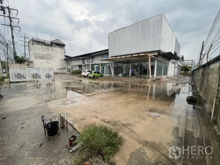 Warehouse for rent in Prawet, Bangkok - Industrial warehouse exterior with large concrete yard and glass-fronted office.