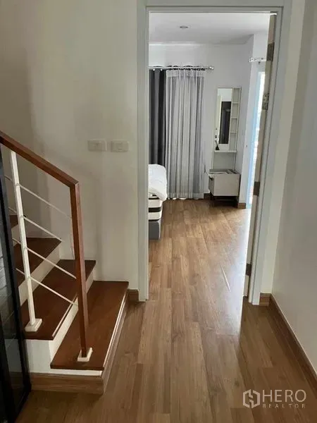 Townhouse for rent in Suan Luang, Bangkok - Upstairs corridor with wooden flooring leading to a bedroom and staircase.