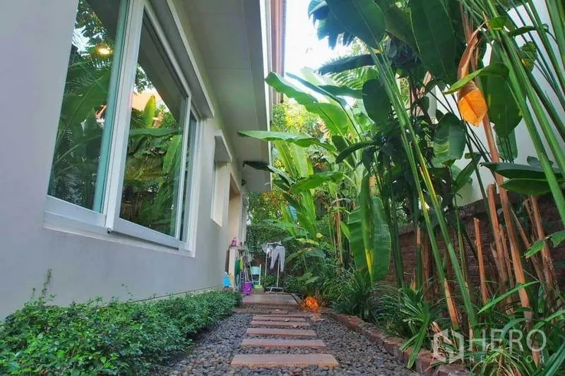 Detached House for rent or sale in Pak Kret, Nonthaburi - Side garden walkway with stepping stones, pebbles and tropical plants along the wall.