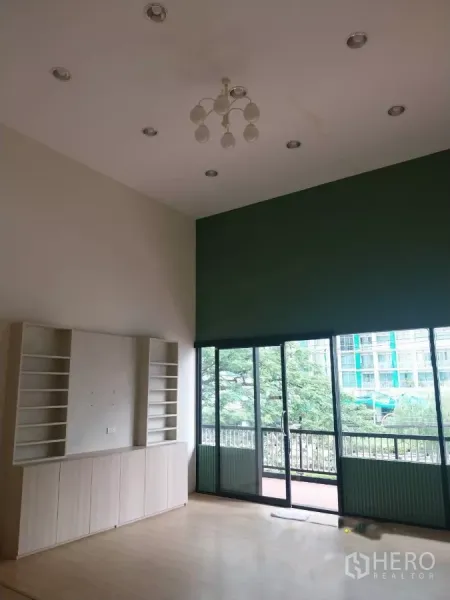 Retail Space for rent - Bright double-height retail interior with chandelier, built-in shelves and sliding glass doors to an outdoor walkway.