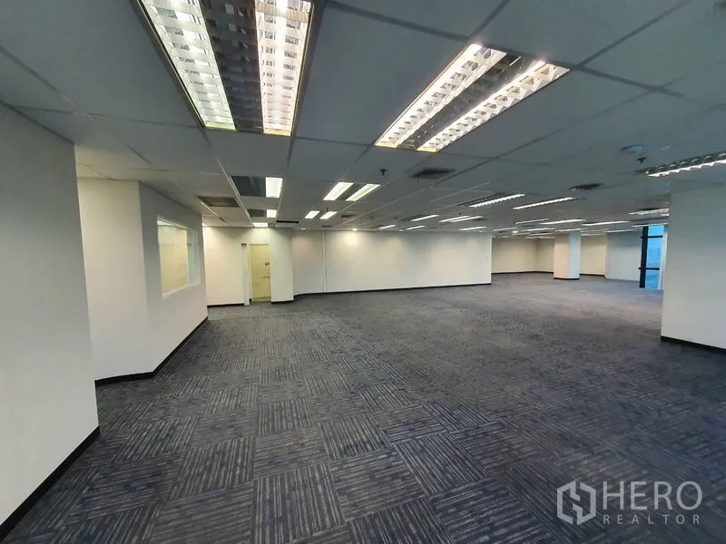 Office Space for rent in Watthana, Bangkok - Large office floor with suspended lighting, columns and an internal glass partition.