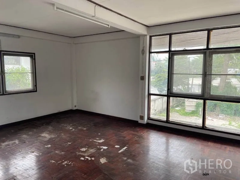 Detached House for rent in Suan Luang, Bangkok - Empty upper-floor room with large corner windows and worn parquet flooring.