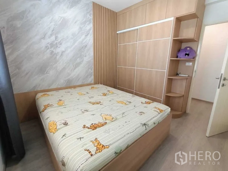 Townhouse for rent in Prawet, Bangkok - Cozy bedroom with marble-look accent wall and floor-to-ceiling wardrobe.