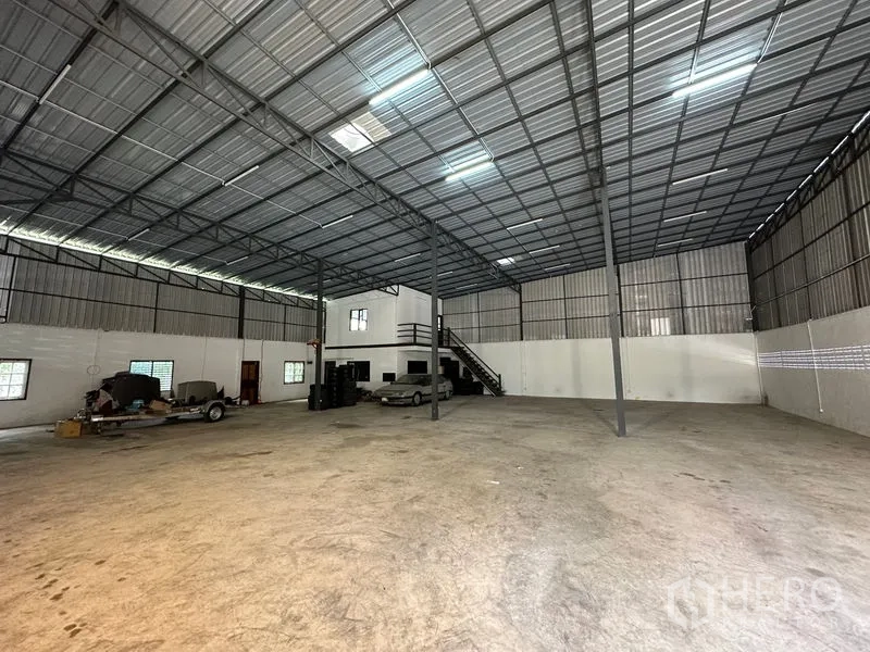 Warehouse for rent in Thanyaburi, Pathum Thani - Open-plan storage area under a metal roof with bright lighting and an office mezzanine.