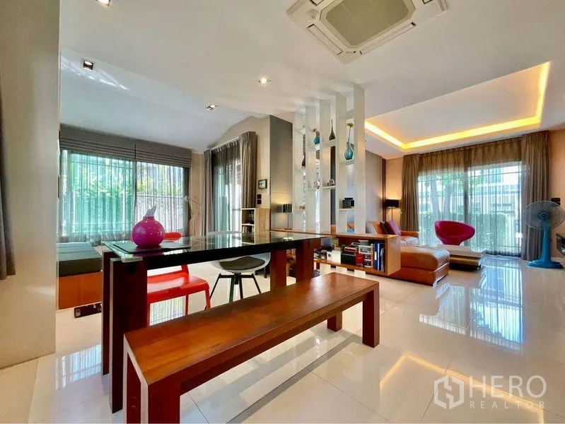 Detached House for sale in Prawet, Bangkok - Bright open-plan dining and living area with glass table, bench seating and cove lighting.