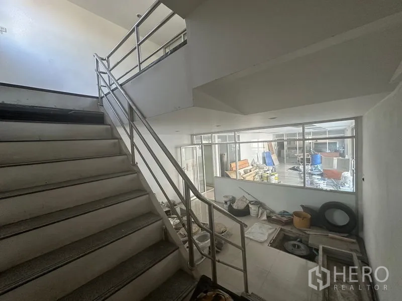 Warehouse for rent in Saphan Sung, Bangkok - Internal staircase with stainless railing overlooking workshop and storage area.