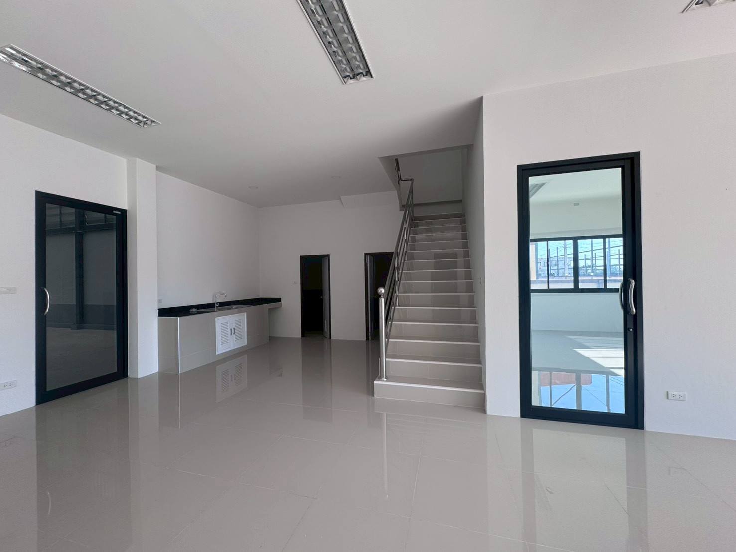 Factory for sale in Mueang Samut Sakhon, Samut Sakhon - Ground-floor office showing pantry counter, staircase to upper level and glass doors.