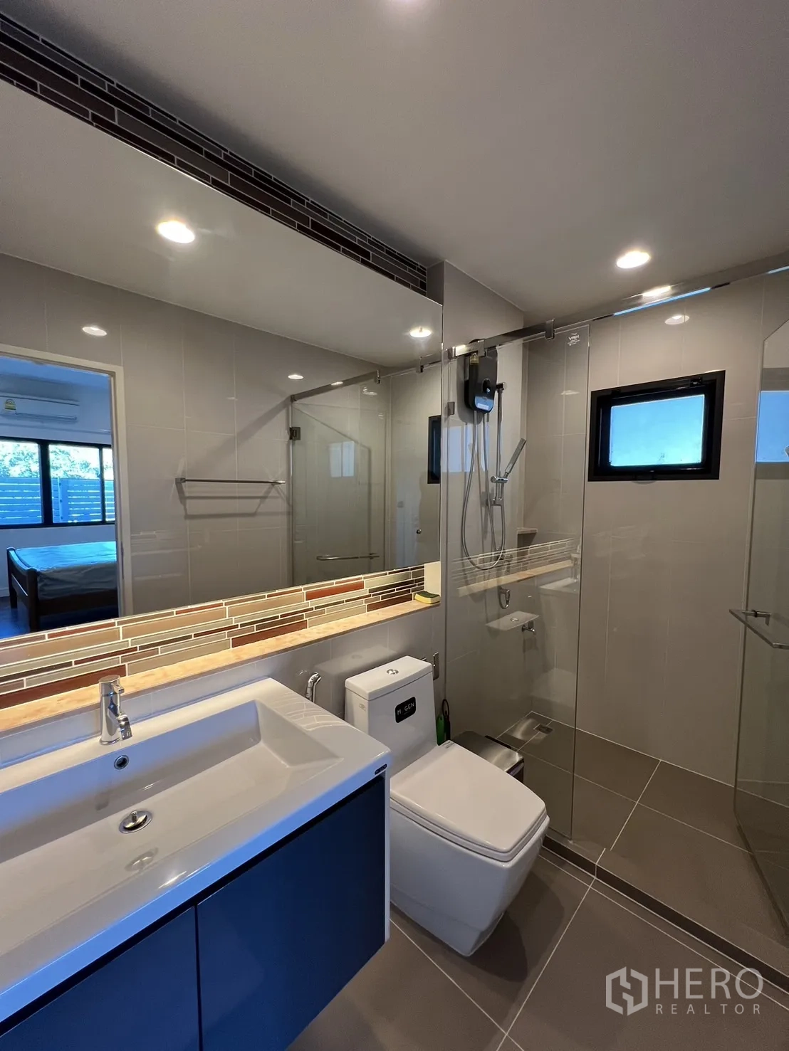 Detached House for rent or sale in Bang Kapi, Bangkok - Ensuite bathroom with shower, toilet and wide mirror above the sink.
