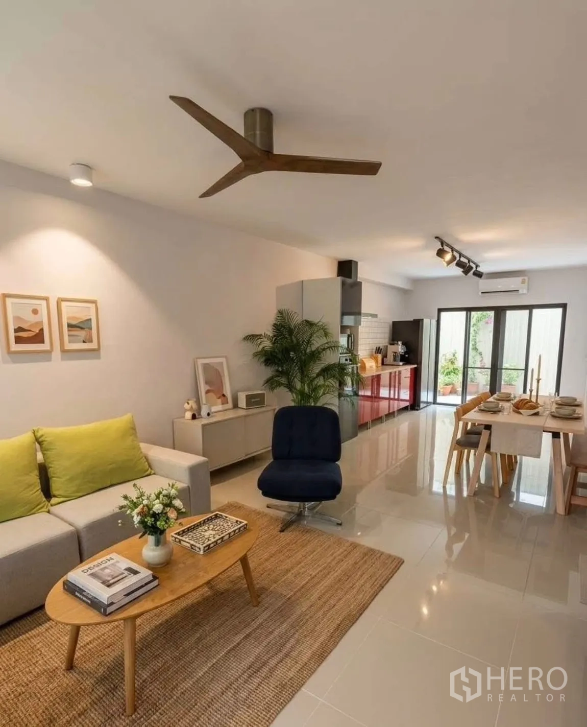 Townhouse for rent in Suan Luang, Bangkok - Open-plan living and dining area with sofa, rug, dining table and kitchen cabinetry.