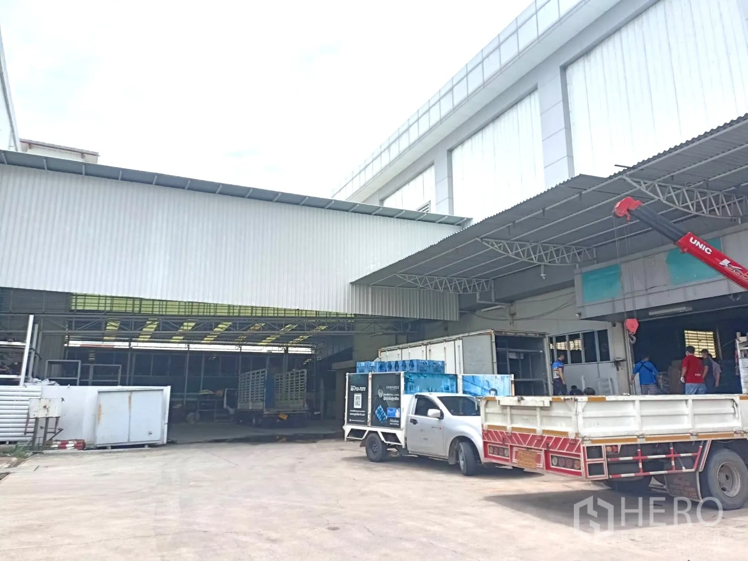Warehouse for rent in Lam Luk Ka, Pathum Thani - Covered loading bay with a crane truck and utility vehicles in the yard.
