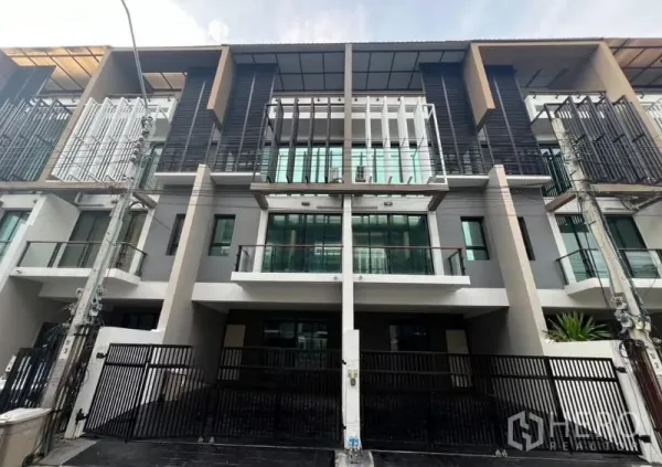 Townhouse for rent or sale in Khlong Toei, Bangkok - Modern multi‑level townhouse facade with glass balconies, vertical screens and a gated entrance on an urban street.