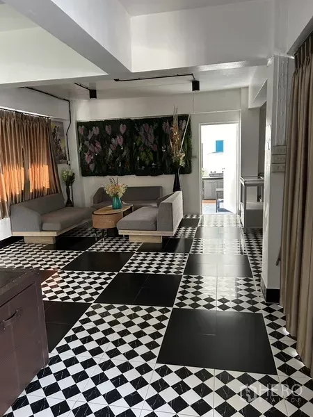 Home Office for rent or sale in Phra Khanong, Bangkok - Lounge area with checkerboard tile floor, neutral sofas and long curtains.