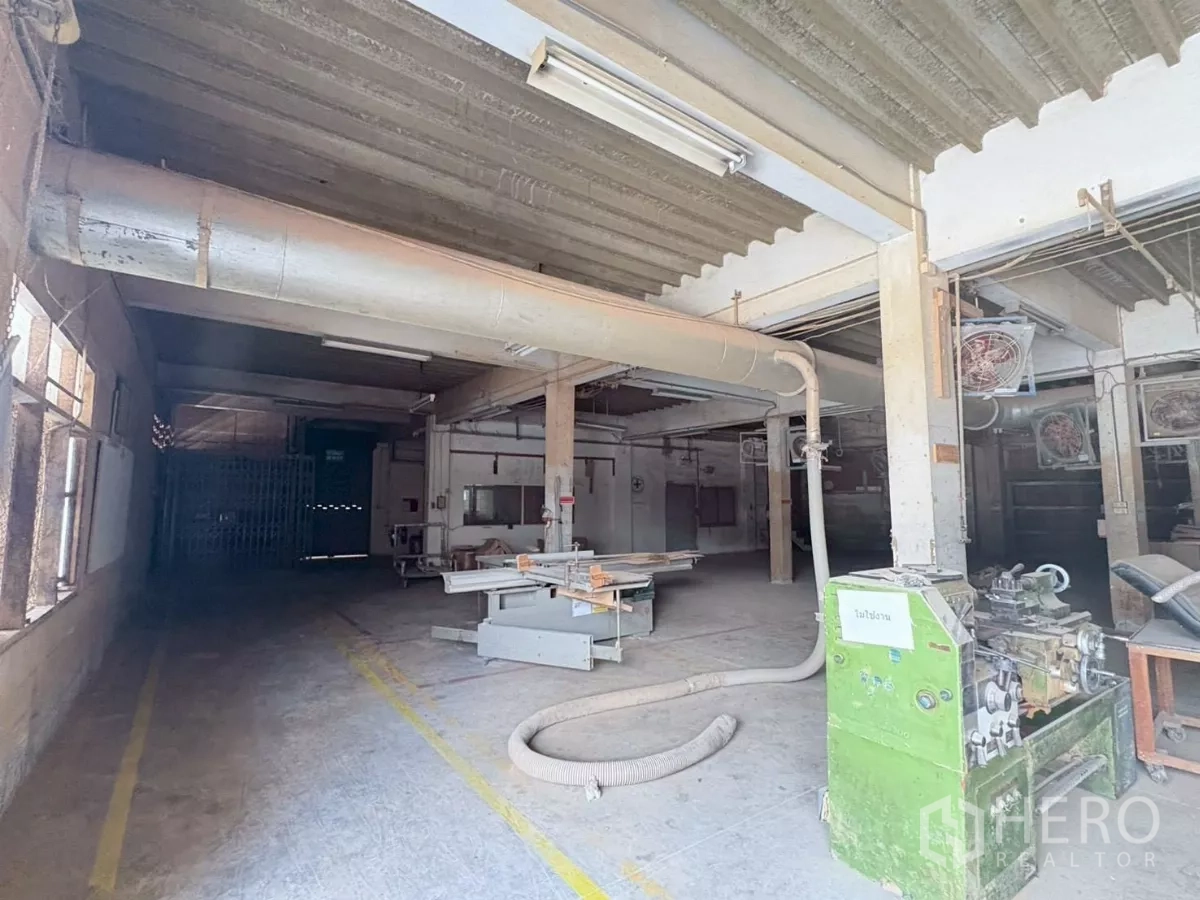 Factory for rent or sale in Bang Khun Thian, Bangkok - Workshop with saw table, dust-extraction ducting and industrial machines.