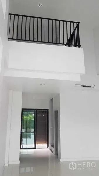 Shophouse for rent or sale in Bang Na, Bangkok - Bright double-height lobby with white walls, glossy floor and black metal mezzanine railing.