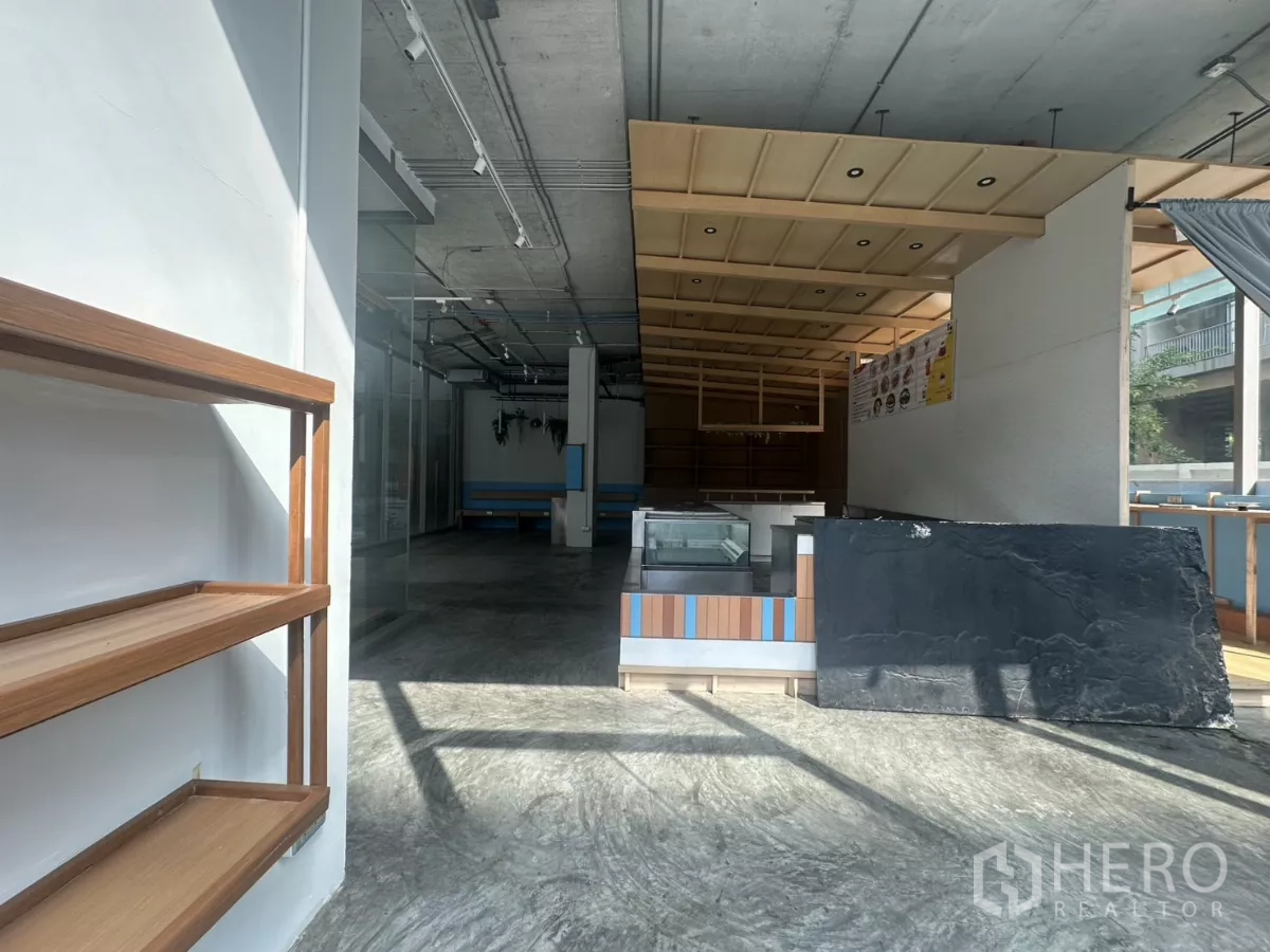 Retail Space for rent - Sunlit entrance zone with wall-mounted shelves, polished concrete floor, and an island counter.