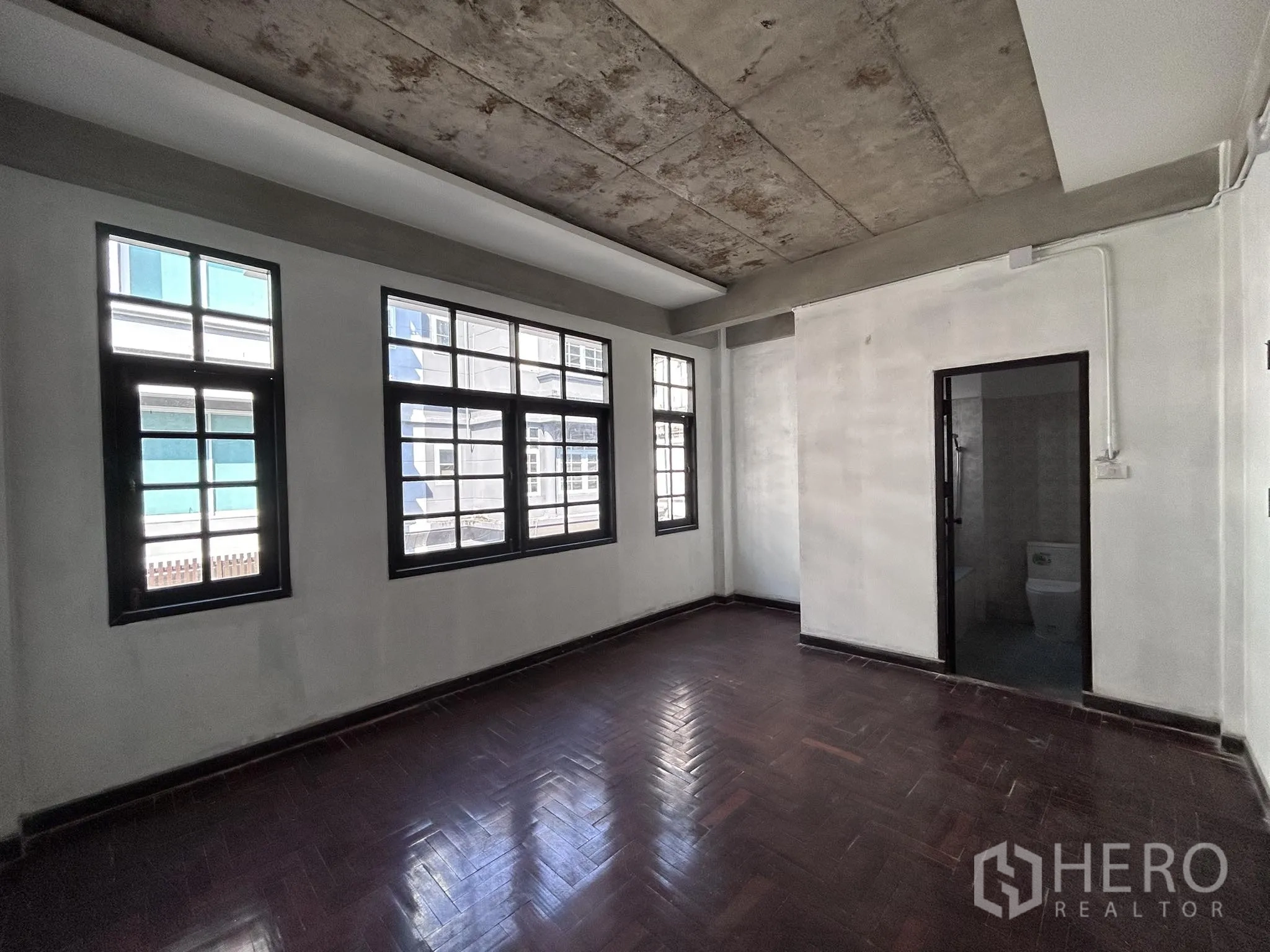 Home Office for rent or sale in Watthana, Bangkok - Large room featuring multiple windows, parquet floor and bathroom access.