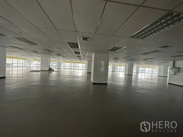 Office Space for rent - Expansive open‑plan office floor with drop ceiling, columns, and wide windows offering city views.