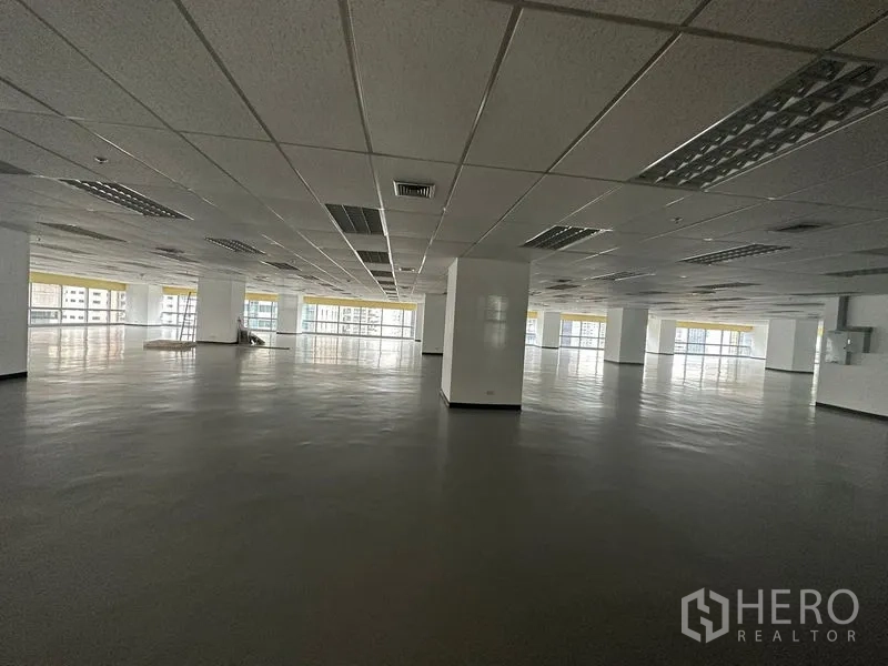 Office Space for rent - Expansive open‑plan office floor with drop ceiling, columns, and wide windows offering city views.