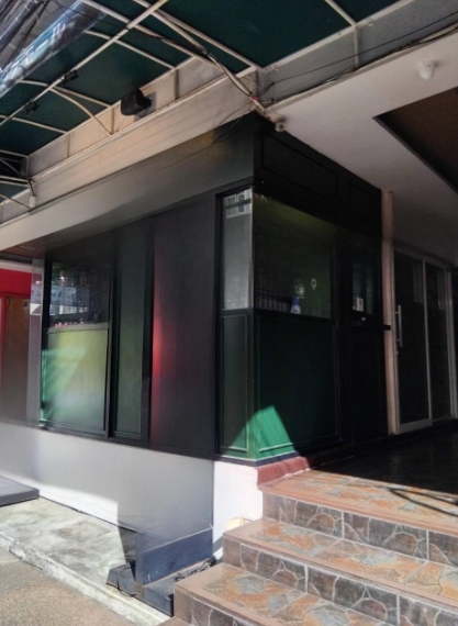 零售空间 出租在Watthana, Bangkok - 转角商铺，旁有台阶与棚篷，磨砂玻璃窗面向繁忙的素坤逸小街。